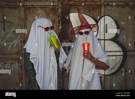 Funny image of two people in ghost costumes drinking from a cu Stock Photo - Alamy