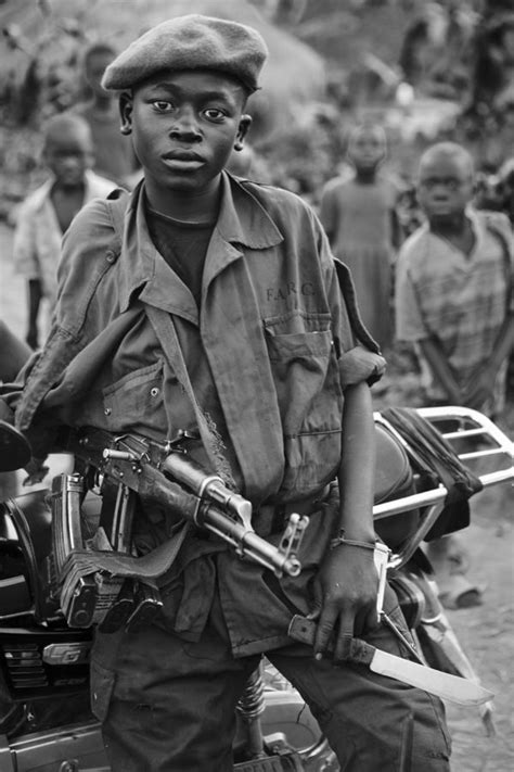 An African child soldier is holding his AK47 rifle with a knife in his ...