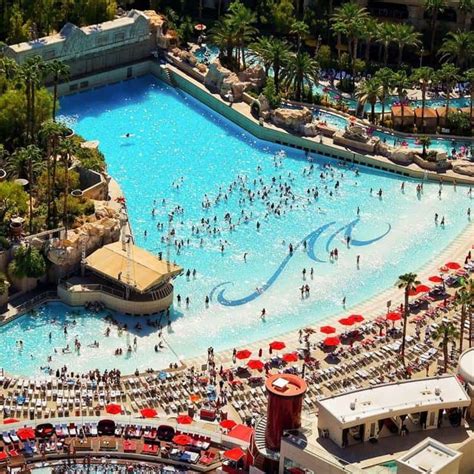 an aerial view of a large swimming pool with many people and umbrellas ...