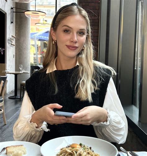 a woman sitting at a table with plates of food and a cell phone in her hand