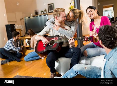 Happy friends playing guitar and listening to music at home Stock Photo - Alamy