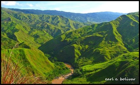 the green mountains are covered with grass and trees in the foreground ...