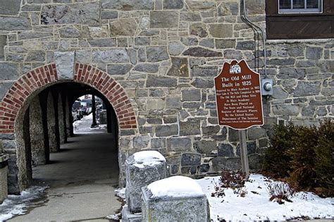 a stone building with a sign on the side and snow covered ground around it,