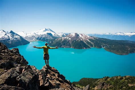 a man standing on top of a mountain with his arms outstretched in front of him