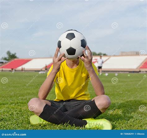 Boy Sitting on the Grass in a Football Stadium, and Holds a Soccer Ball ...