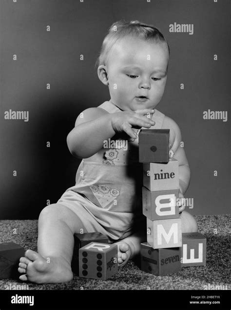 Baby sitting on carpet stacking blocks Stock Photo - Alamy