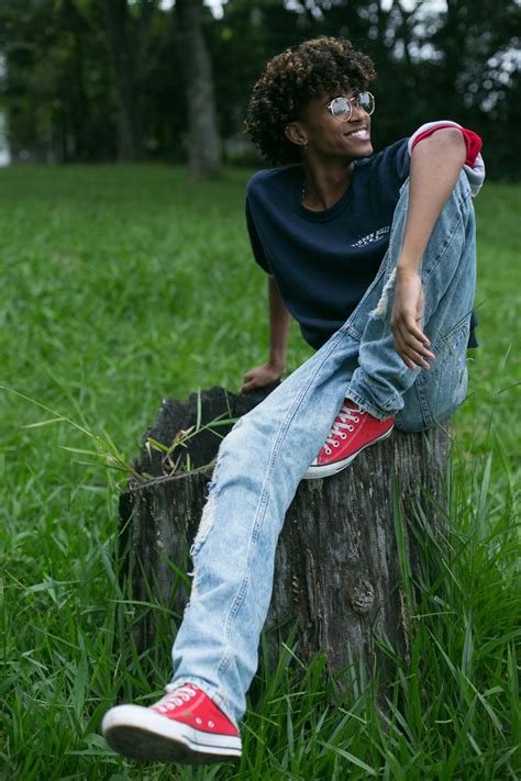 Man in Blue Crew Neck T-shirt and Blue Denim Jeans Sitting on Tree Log · Free Stock Photo