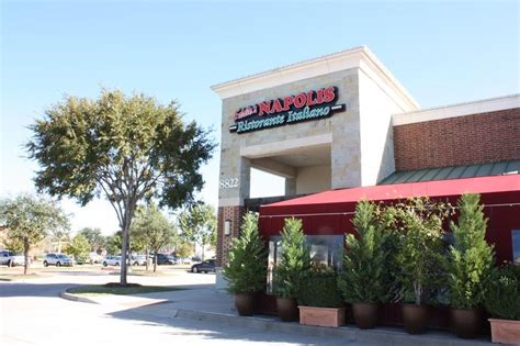 the outside of a restaurant with red awnings and potted plants in front