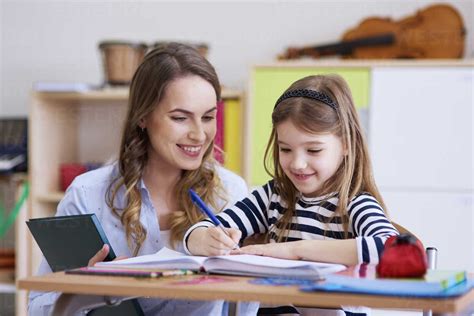 Smiling teacher with schoolgirl in class stock photo