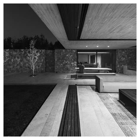 black and white photograph of the interior of a modern house at night with outdoor furniture