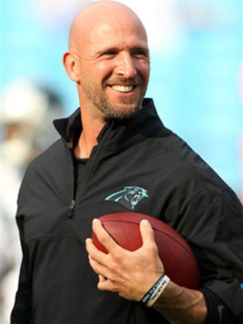 a bald man holding a football on top of a field