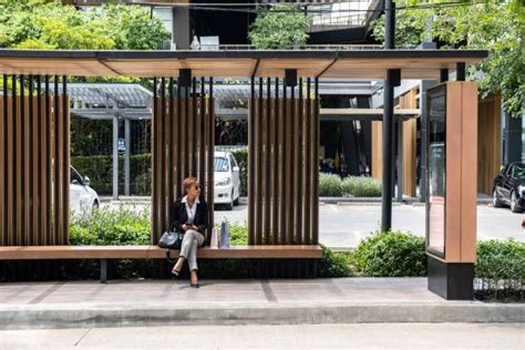 a woman sitting on top of a wooden bench next to a tree filled park area