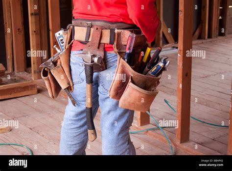 Carpenter wearing a leather tool belt with an assortment of tools on a construction job Stock ...