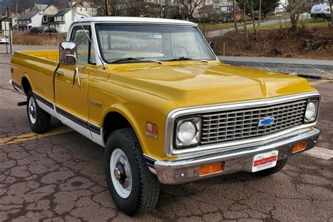 This 1971 Chevrolet K20 Custom is a four-wheel-drive pickup that is finished in yellow and white ...