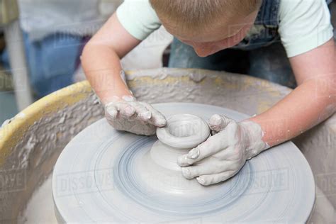 Boy shaping clay on potter's wheel - Stock Photo - Dissolve