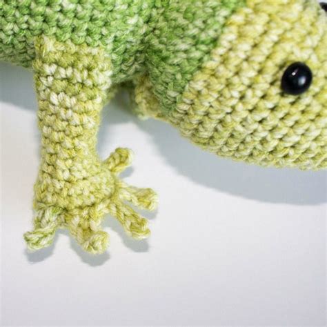 a stuffed toy lizard with black eyes and green body sitting on top of a white surface