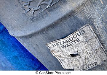 Hazardous waste barrel. A black metal barrel with a yellow hazardous waste label on an isolated ...