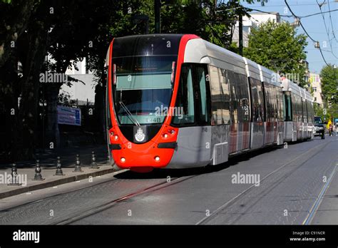 Red Alstom Citadis tram in a narrow street in the European part of ...