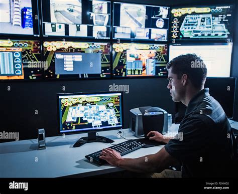 Hispanic security guard watching monitors in control room Stock Photo ...