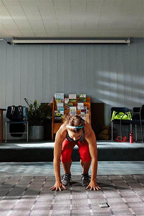 a man in red shorts and black shirt doing push ups on a tile floor with his hands behind his head