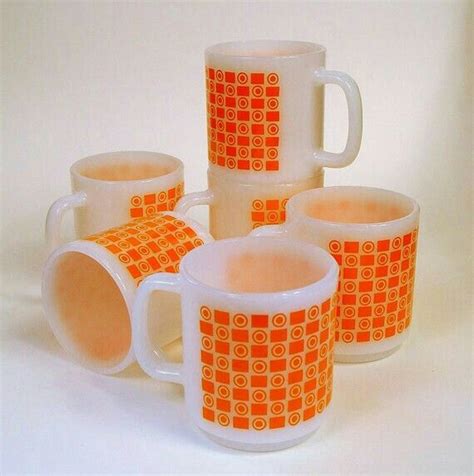 five orange and white coffee mugs sitting next to each other on a white surface