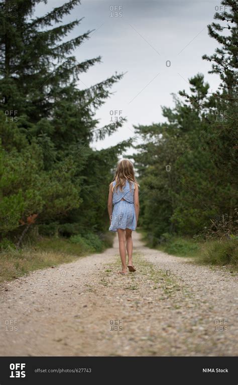 Rear view of girl walking alone in desolate forest stock photo - OFFSET