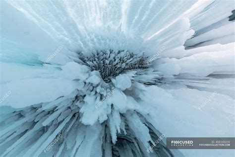 From below of huge icicles hanging from rocky cave near Lake Baikal in winter as abstract ...