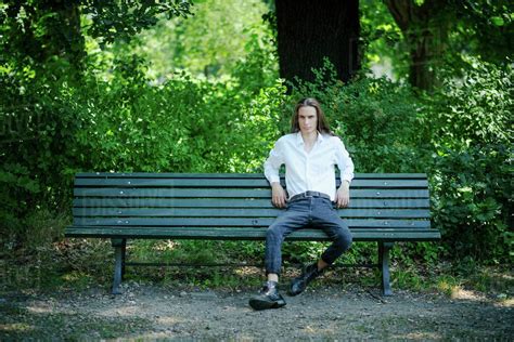 Portrait confident young man sitting on park bench - Stock Photo - Dissolve