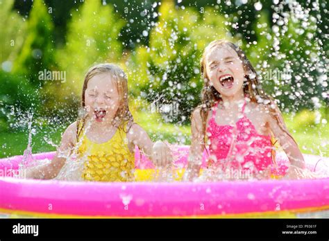 Adorable little girls playing in inflatable baby pool. Happy kids ...