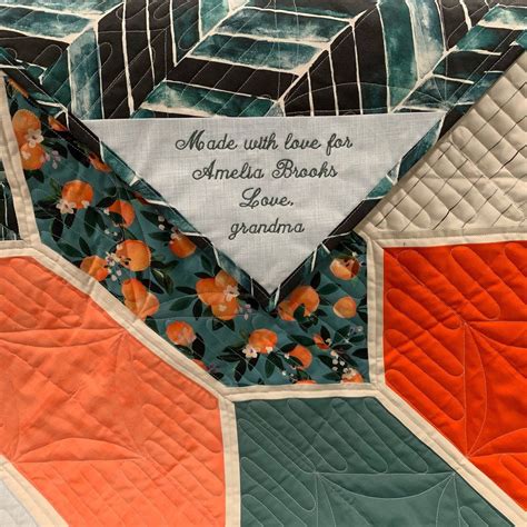 an orange and green patchwork quilt with words written on the top, along with flowers