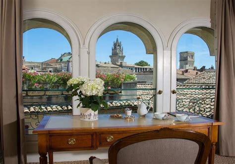 a desk with flowers on it in front of three arched windows that look ...