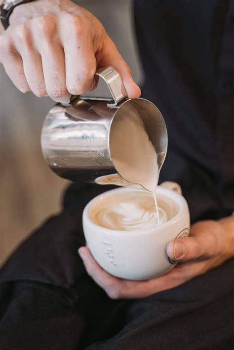 Person Pouring Milk into the Cup with Coffee · Free Stock Photo