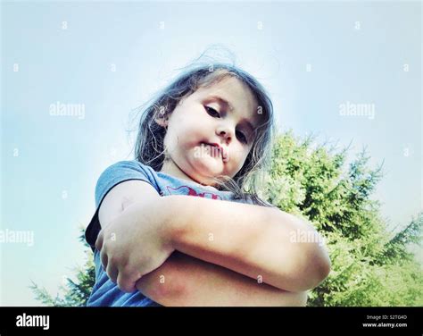 Young girl looking down with arms crossed and unimpressed expression ...