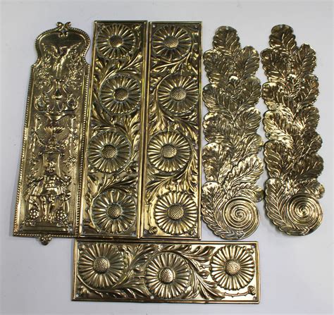 A set of four late Victorian Arts and Crafts style pressed brass rectangular door plates, decorated