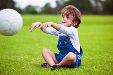 Young Girl Sitting On A Grass Throwing Ball Royalty Free Stock Image - Image: 13791746