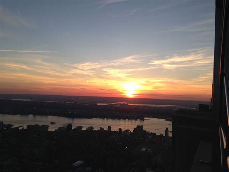 the sun is setting over a large body of water with buildings in the foreground