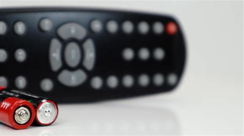 Black TV remote control with AAA alkaline batteries in red and white on ...