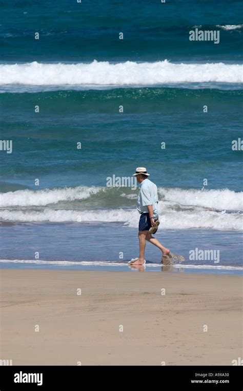 Man walking alone on a beach Stock Photo - Alamy