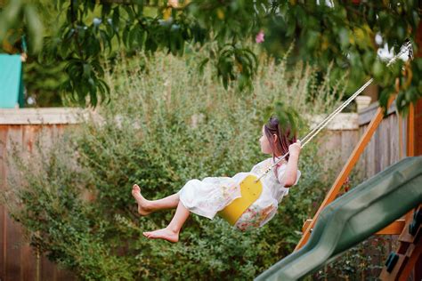 A Happy Barefoot Girl Swings On A Playlet Under A Tree In Summer ...