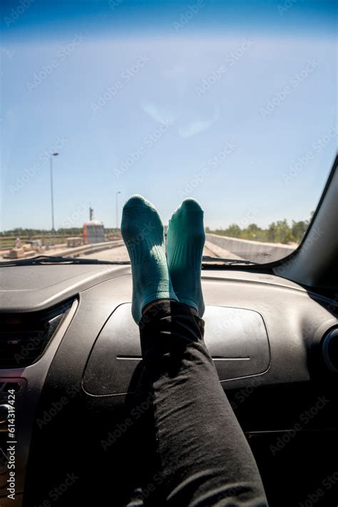 Feet on the dashboard of the car while traveling on route. Stock Photo | Adobe Stock