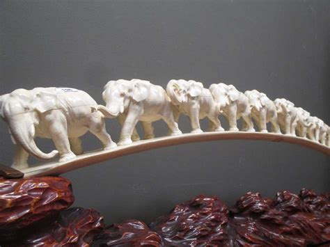 An ivory elephant tusk carved with twelve graduated elephants on a carved naturalistic stand ...