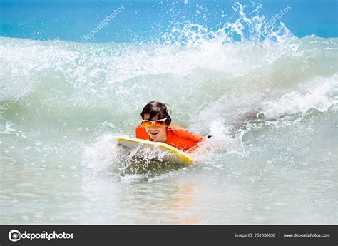 Child surfing on tropical beach. Surfer in ocean. Stock Photo by ©FamVeldman 251336050