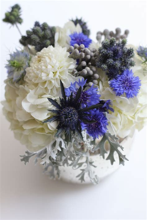 a white vase filled with blue and white flowers