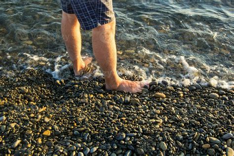 man walking alone on the pebble beach in the sunset 23881819 Stock Photo at Vecteezy