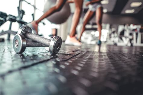 Dumbbell on a Flor in Fitness Gym with Legs in Background Stock Photo - Image of barbell ...