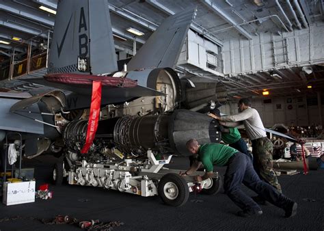 move an engine to be attached to an F/A-18F Super Hornet in the hangar ...