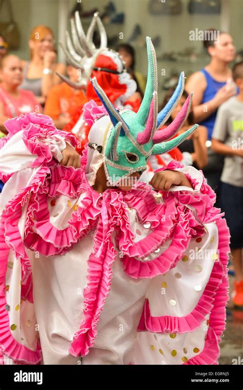 Pink and white masked Vejigante playing during a parade in the streets of Ponce, Puerto Rico ...