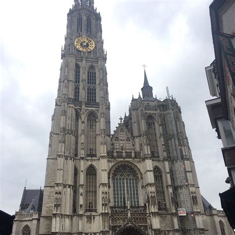 a large cathedral with a clock on it's side and people walking in front