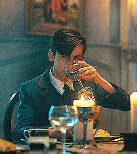 a man sitting at a table drinking from a wine glass with candles in the background