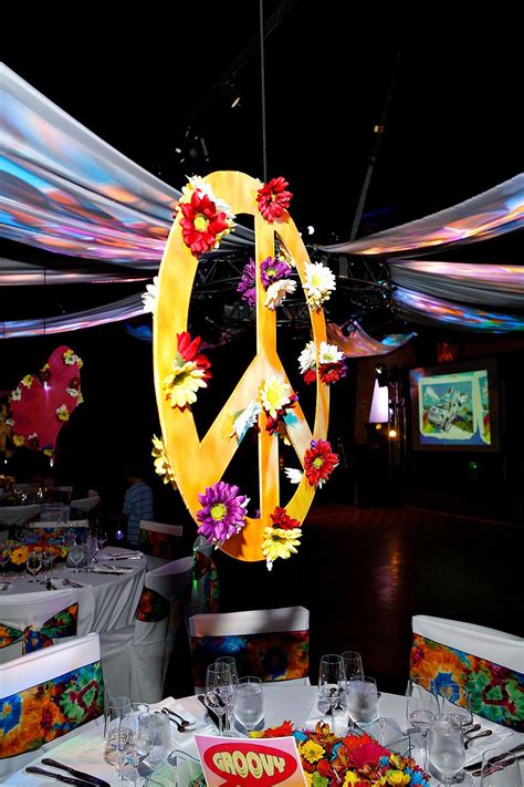 Suspended Peace Signs centerpieces adorned with flowers for 60's inspired celebration. Decor by ...